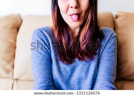 close up portrait of a young woman with her tongue out. Fun at home, indoors