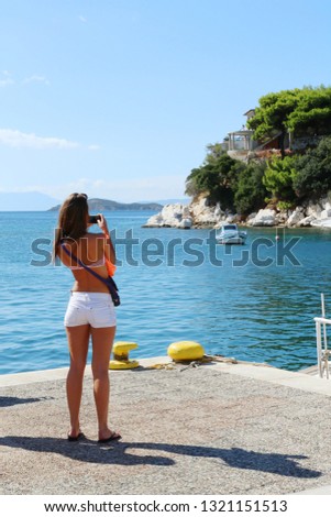 Beautiful girl takes pictures on the shore of the skeleton of Skiathos, Greece.