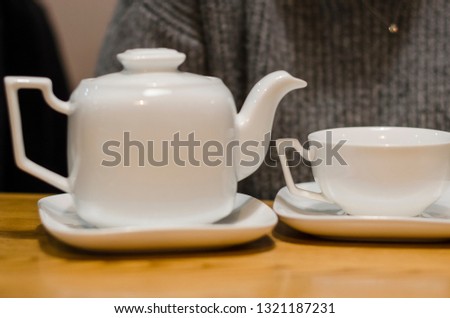 White tea set of a cup and teapot concept. Eating breakfast on the wooden table background. Dinking a hot drink in the coffee shop.