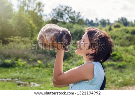 young woman with the rabbit. happy woman holding cute fluffy Bunny.Friendship with Easter Bunny. Spring photo with beautiful young girl with her Bunny. Girl is holding a cute little rabbit
