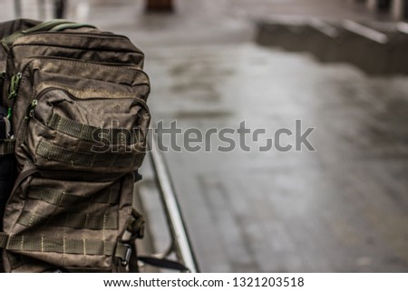 olive military backpack equipment concept wallpaper pattern photography with unfocused urban gray background environment and empty copy space for your text or inscription 