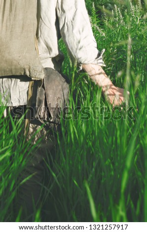 soldier is on the field touching the hand of tall grass