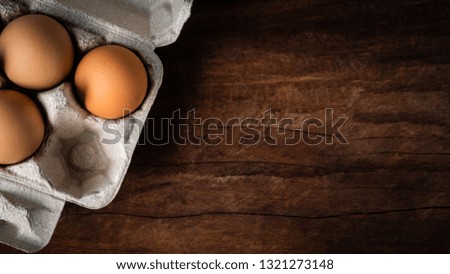 Fresh brown eggs in a carton box was placed on a wooden table to prepare food. Have copyspace to enter text. In aspect ratio 16: 9. Useful for health and easy to find according to the supermarket.