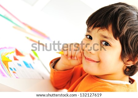 Cute little schoolboy drawing an house and looking at camera