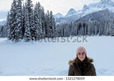 A young woman posing with the forests of Island Lake in Fernie, British Columbia, Canada behind.  The majestic winter background is an absolutely beautiful place to go hiking with fresh fallen snow.