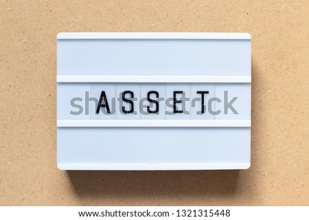 White lightbox with word asset on wood background