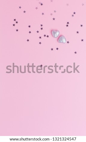 Top view of two silver hearts up below silver stars confetti on pink background with copy space. Concept of wedding, Valentine's day, date, celebrate, woman blog. Template for blog, postcards, flyers
