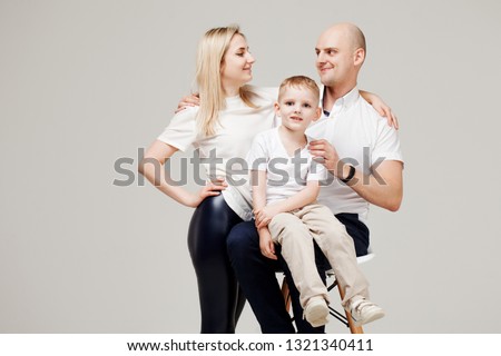 Mom dad and son, stylish family portrait on light grey background. Happy young family