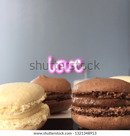 Dark and white chocolate macarons on plate and marble tray on wooden table. Love sign in background