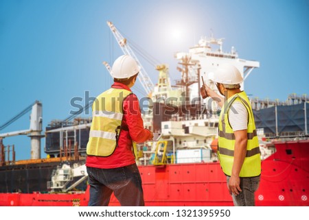 foreman, supervisor, port controller, loading master in charge of working in the dock at workplace, control and communication to the teamwork by walkie talkie radio for job done in the same direction Royalty-Free Stock Photo #1321395950