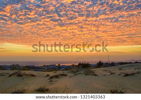 Rare sunset view from the sand dunes of the village Mui Ne, the sea and the distant horizon. Detailed clouds illuminated by low sun. Asia, Vietnam, February.