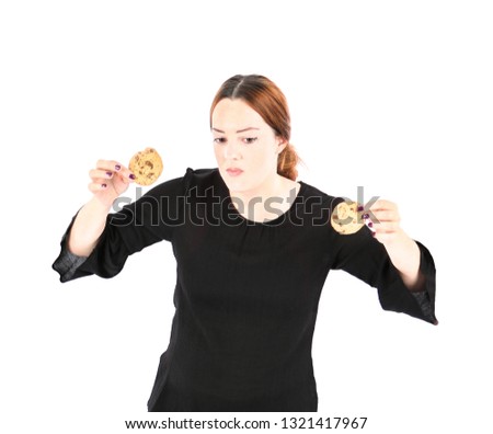 Young woman holding two cookies while acting funny against a white background