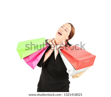 Excited young woman laughing while holding different color shopping bags against a white background