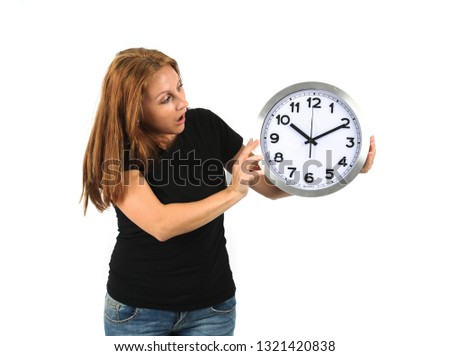Surprised young womb holding a clock to one side while looking at it against a white background