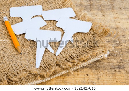 White labels-markers for plants lie on burlap, on wooden  background. Studio Photo