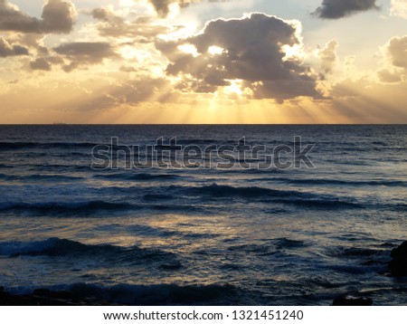 Sunburst behind clouds above seascape