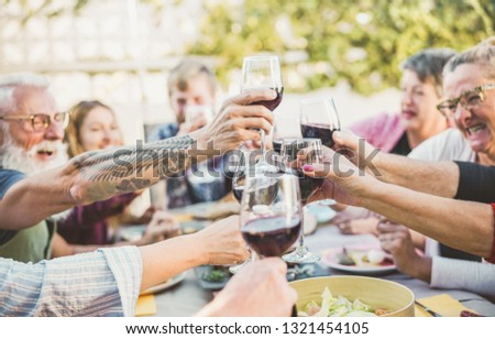 Happy trendy family cheering with red wine at barbecue dinner outdoor - Different age of people having fun at sunday meal - Food, taste and summer concept - Focus on right bottom hand glass