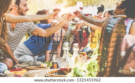 Happy friends cheering with wine glasses at picnic dinner outdoor - Young students having fun at bbq in winery vineyard - Food, summer lifestyle and youth concept - Focus on center glasses