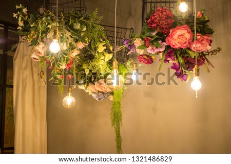 A beautiful composition of lights and flowers hanging from a cealing.