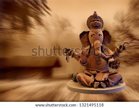 Lord Ganpati for Ganesh Chaturthi is brown in color against old buildings and trees. Sweet god. The patron of arts and sciences and the deva of intellect, wisdom and wealth.