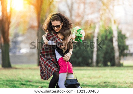 Mother and daughter playing in the park, daughter surprising mother with a gift, celebrating womens day