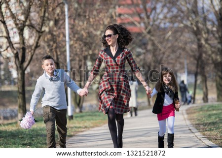 Mother together with son and daughter take a walk through the park casually walking enjoying the sunny day