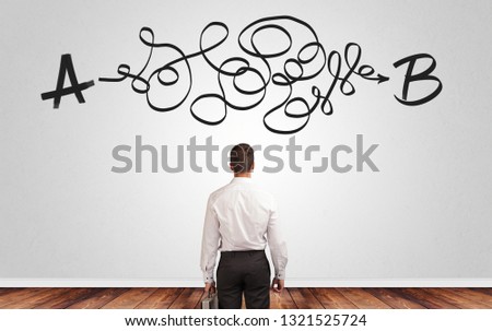 Businessman looking for connection between two things while standing in front of a wall