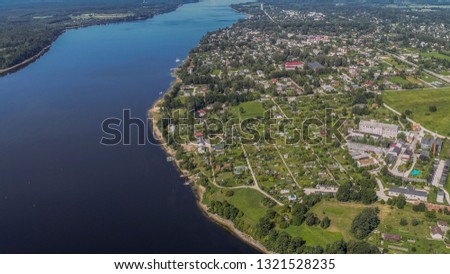 river view from sky with city near water and green grass and trees. National park territory.