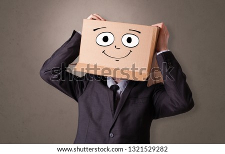 Young boy standing and gesturing with a cardboard box on his head