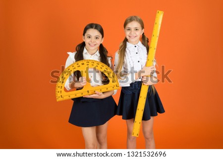 Having a private lesson. Cute schoolgirls holding protractor and ruler. School children with measuring instruments. Little girls ready for geometry lesson. Small girls are back to school.