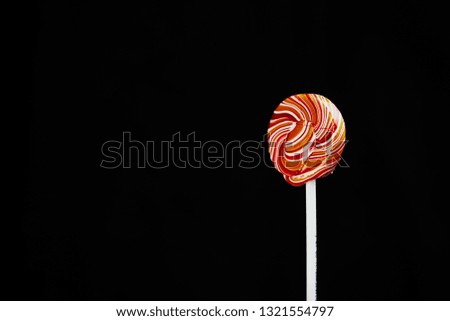 red, round colored Lollipop on black background