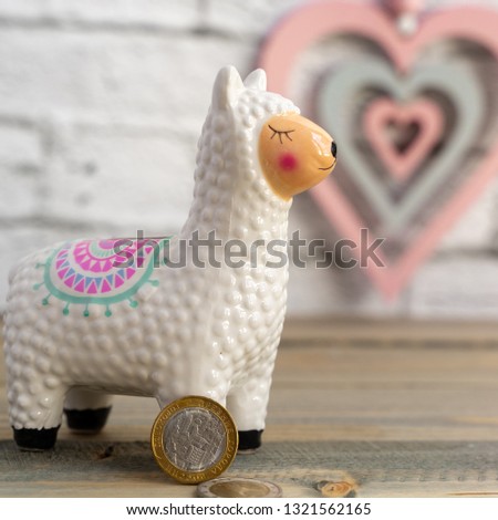 Llama money box on the table with hearts on white background, selected focus, toned, copy space