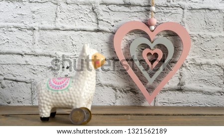 Llama money box on the table with hearts on white background, selected focus, toned, copy space