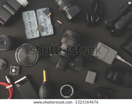 top view of work space photographer with digital camera, flash, cleaning kit, memory card and camera accessory on black table background.
