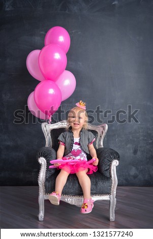 themed birthday for a fun emotional girl of the blonde 2 years old smash the cake in pink color on a black background. stylized photo session tradition with sweet decor and balloons