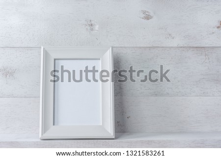white blank photo frame on wooden shelf and wall