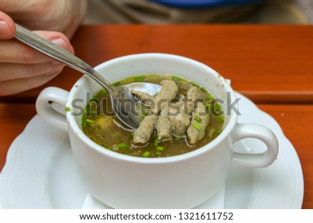 Closeup young man eating hot soup in beer garden or restaurant