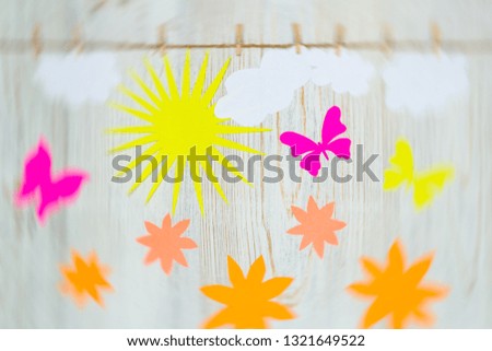 Good weather, bright sunny day concept. Clouds, sun, flowers and paper butterflies are attached with clothespins. Flat lay.