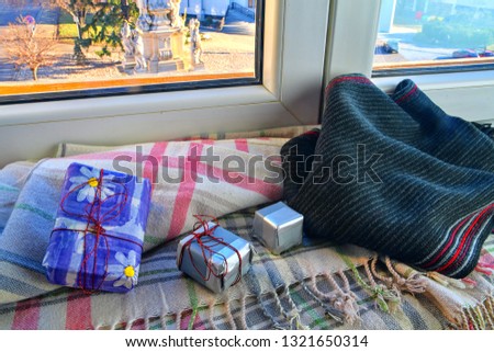 Holidays, winter, celebration and still life concept - window sill, gift boxes, warm scarf at home. Romantic still life. 
