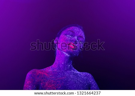Portrait of a beautiful girl purple alien. Ultraviolet body art blue night sky with stars and pink jellyfish, on violet background.