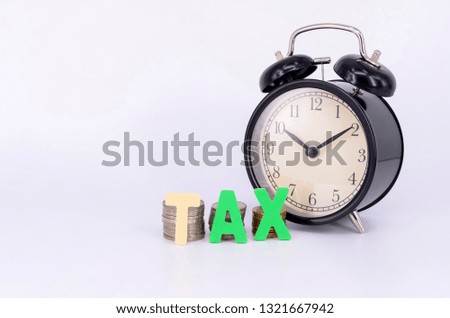 Alarm clock and coins with TAX on white background. Selective focus.