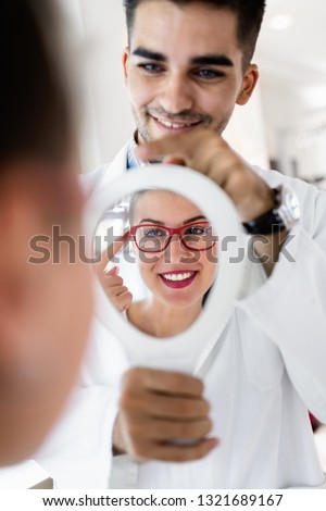 Young optometrist helps customer to choose right eyeglasses Royalty-Free Stock Photo #1321689167