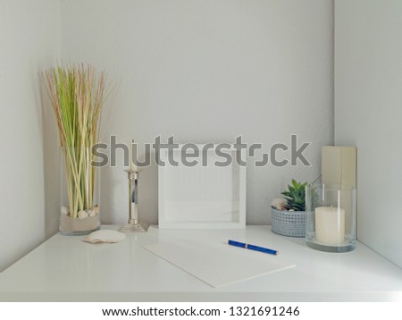 modern white desk interior design with decoration elements, frame for pictures and white wall in the background