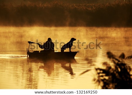 Silhouette of fisher and dog sitting in boat Royalty-Free Stock Photo #132169250