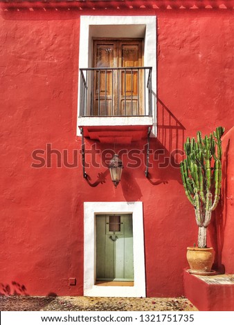 Typical mediterranean spanish house with red facade, balcony and plants in Ibiza, Spain. Architecture, buildings and traditional concept. 