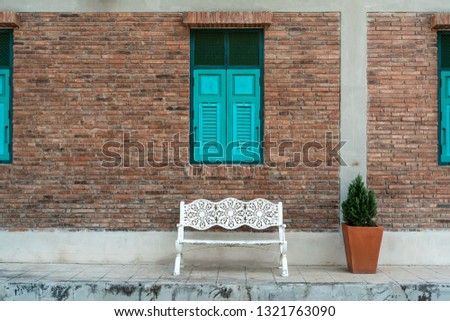 White bench with brick wall with blue window, vintage style