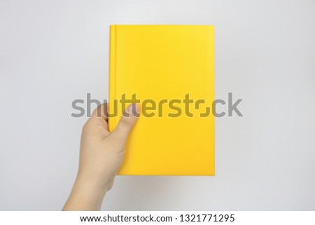 A hand is holding a book. A hand is holding a yellow notebook. On a white background. Hand holding photo frame love