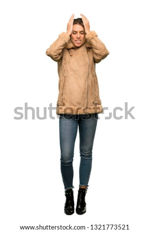 A full-length shot of a Blonde woman with a coat frustrated and takes hands on head over isolated white background