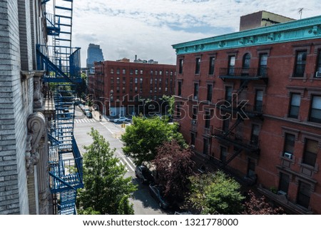Overview of a street with its old typical houses and people around in the Harlem neighborhood in Manhattan, New York City, USA
