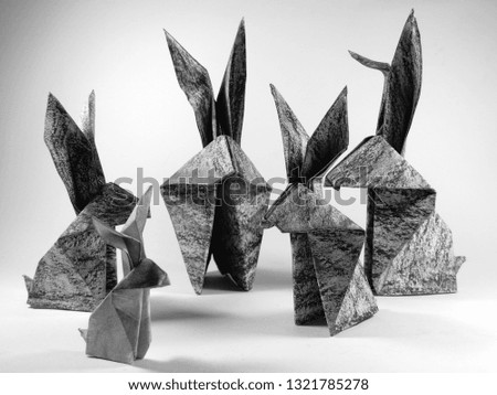 a group of easter bunnies folded in the manner of origami, small and tall bunnies in black and white